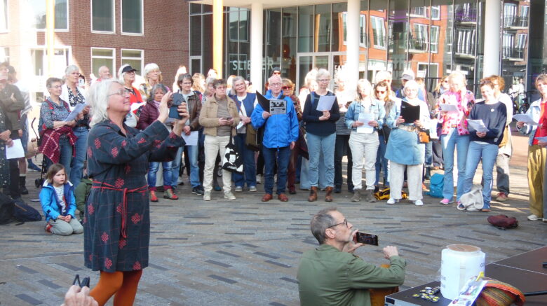 "Een groep mensen verzameld op het Zaailand in Leeuwarden tijdens Internationale Vrouwendag, zingend en steun betuigend aan vrouwenrechten in Afghanistan met het protestlied #Iammysong."